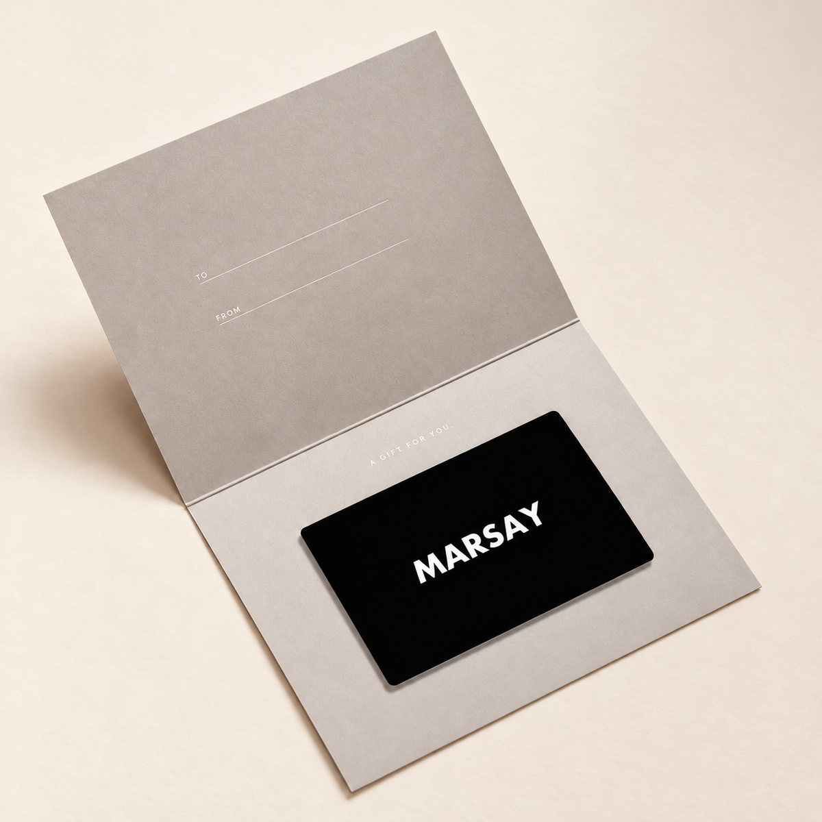 Card cadou MARSAY negru, într-un suport pliabil gri-bej, așezat pe o suprafață crem.