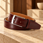 Curea din piele naturală Burgundy, de culoare bordo. Cadru din unghi, pe o suprafață de piatră.