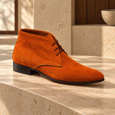 Ghete casual Alberobello Suede din piele întoarsă, de culoare cognac. Vedere din unghi pe o suprafață de piatră, în decor cu lemn.