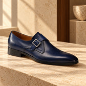Pantofi de piele naturală monkstrap Treviso, de culoare bleumarin. Vedere din unghi pe o suprafață de piatră, în decor cu lemn.