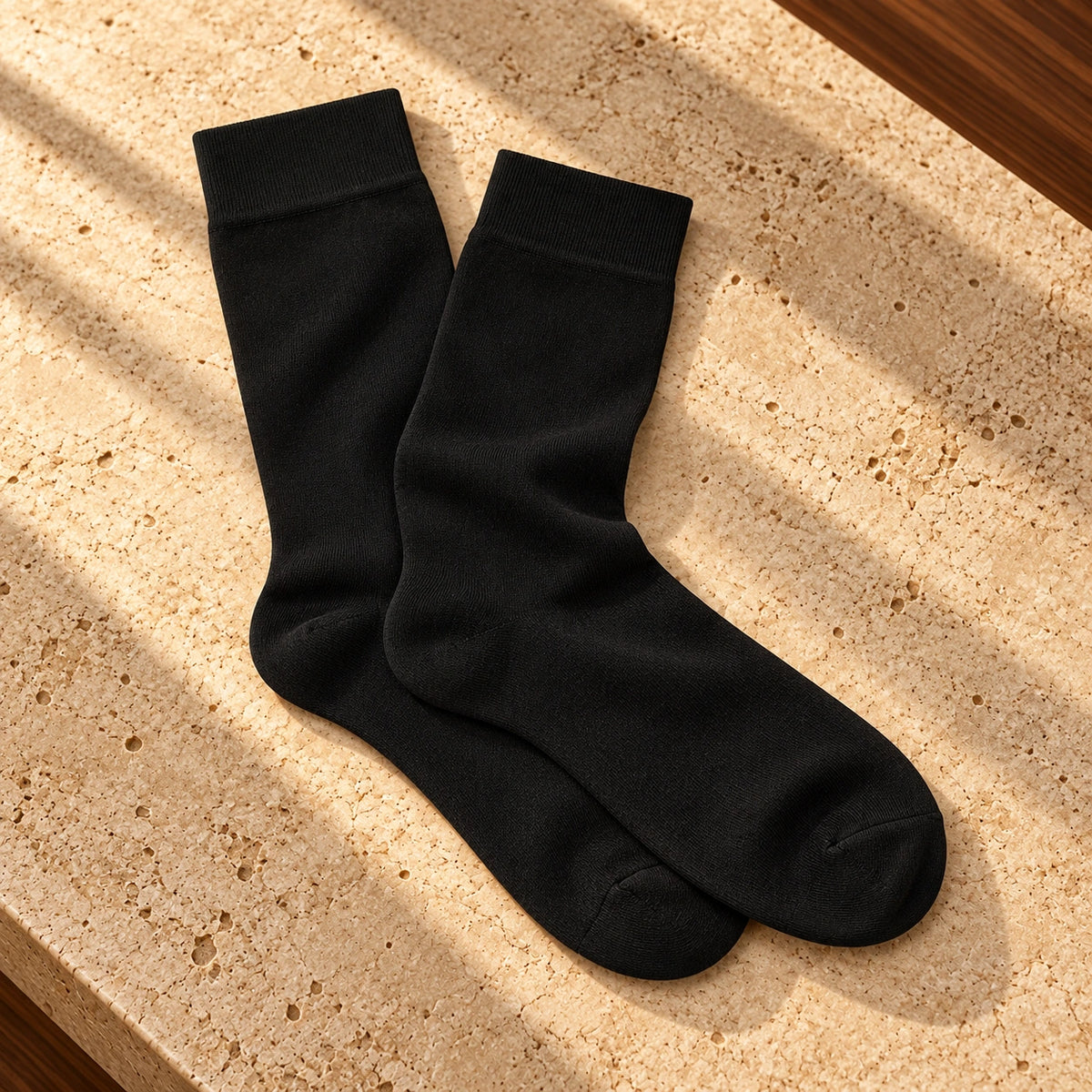 Pereche de șosete Black Tie negre, așezate natural pe o suprafață de piatră.